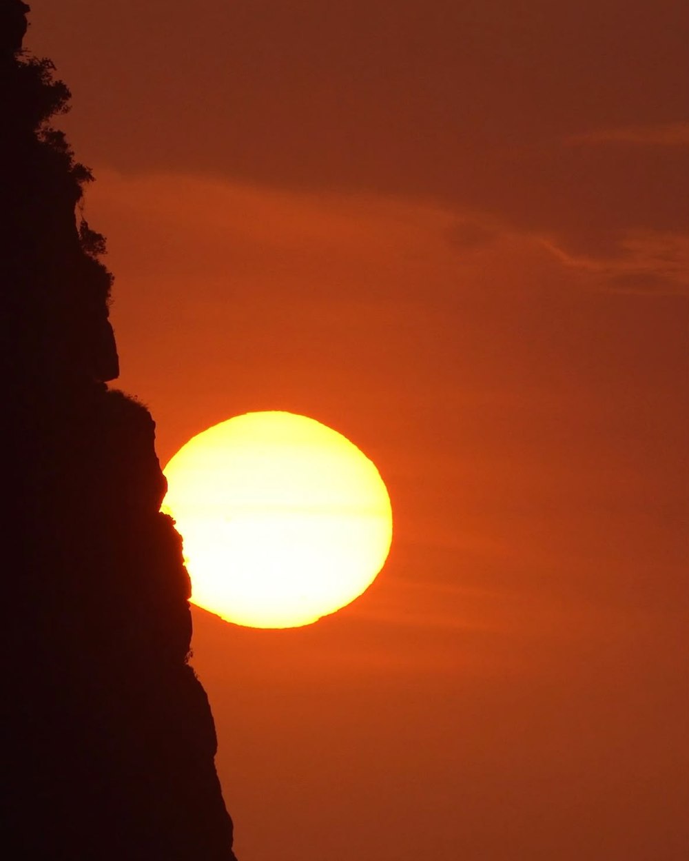 Sun setting behind a coastal cliff in Thailand